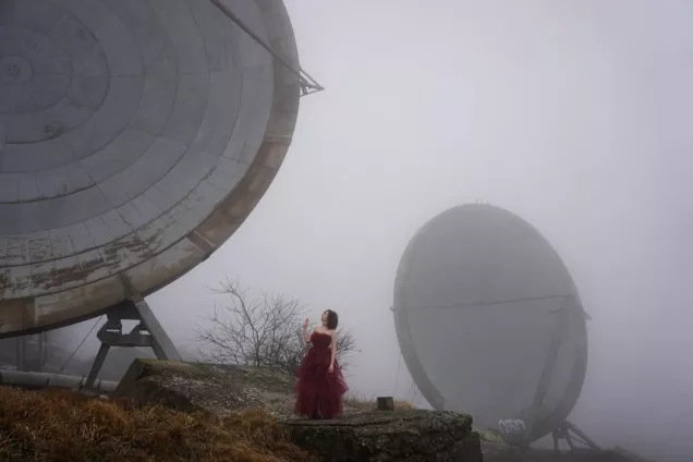 Felicita_Brusoni_photo_Silvia Musso_2.jpeg Woman in a red dress in a foggy landscape with satellite shades. Photo.
