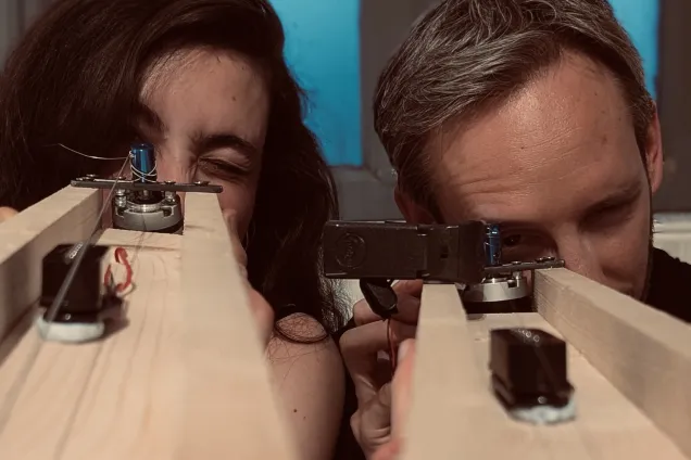 Woman and man looking through a part of an instrument. Photo.