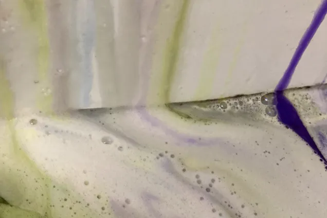 Cleaning fluids in different colours are sprayed onto the wall. Photo.