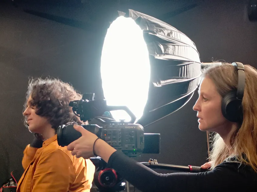 Two persons and a spotlight during a video production. Photo.